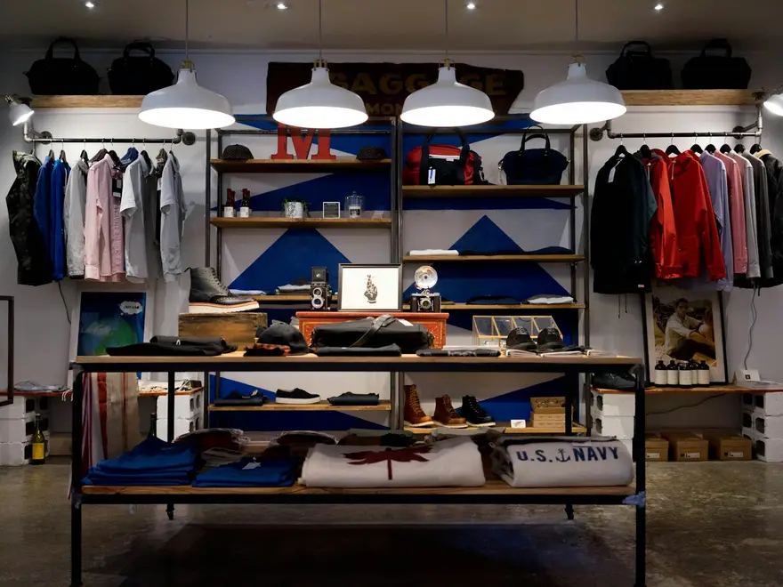 Interior de una tienda de ropa de barrio con la mercancía ordenada en estanterías de madera
