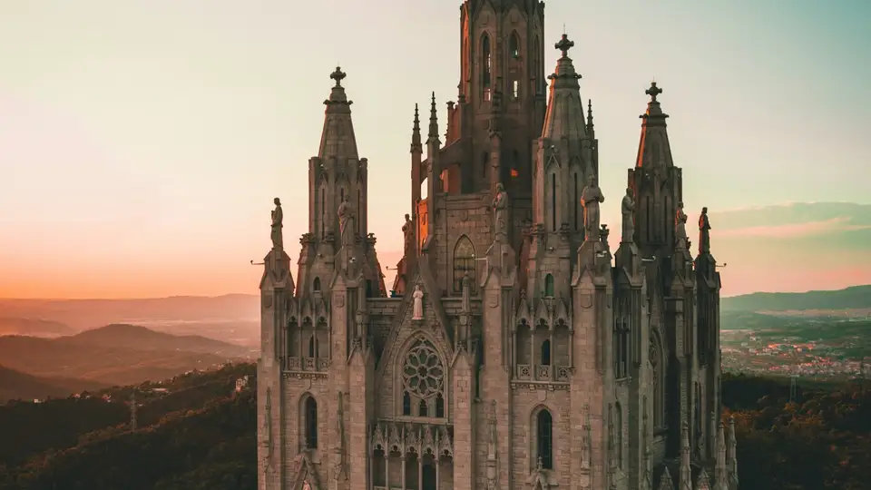 El templo del Tibidabo sobre Barcelona al atardecer, con la ciudad al fondo